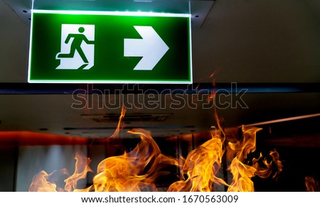 Green fire escape sign hang on the ceiling in the office.