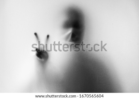 Shadow blur of man wear mask to prevent infection.Hands finger to fight on the glass background.Fight against communicable diseases covid-19.Blur picture.Fight deadly communicable diseases coronavirus