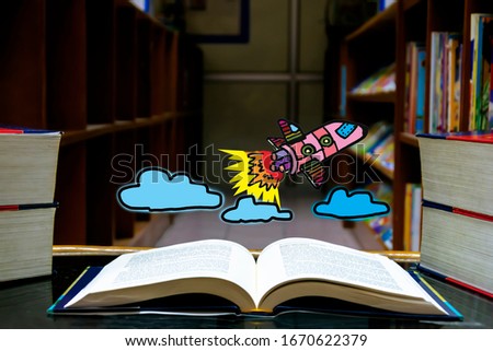 Back to school concept. The atmosphere of the library, with wide open books on the table, Graphics, rockets and clouds floating on the book