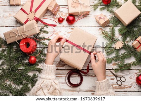 Woman making beautiful Christmas gift at table Royalty-Free Stock Photo #1670639617
