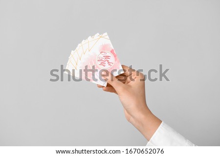 Female hand with business cards of makeup artist on grey background