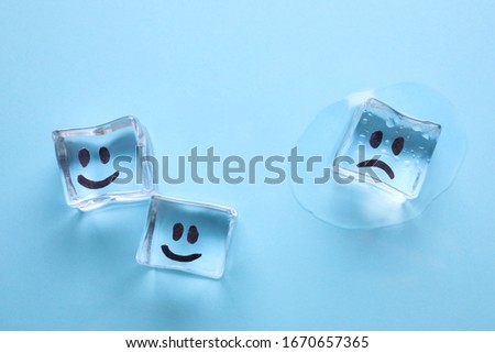 Ice cubes with drawn faces on light blue background, flat lay. Concept of jealousy Royalty-Free Stock Photo #1670657365