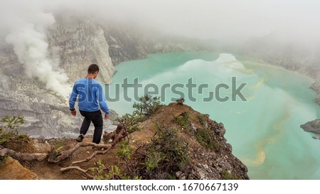 Man goes on the trail ijen smoke sulfuric acid lake blue Indonesia the island of Java