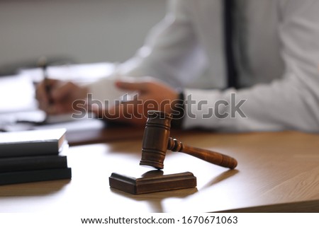 Male lawyer working at table in office, focus on gavel