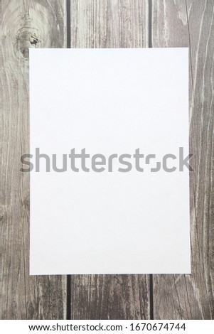 Notepad with a blank white sheet in a checker paper lies on the background of wooden boards
