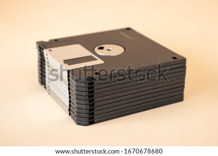 A pile of floppy discs on a beige background