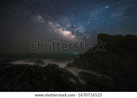 Milky Way on the sea at night with reefs by the sea