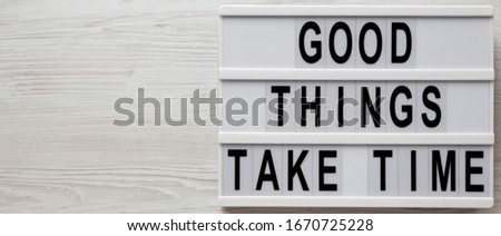 'Good things take time' words on a lightbox on a white wooden surface, top view. Overhead, from above, flat lay. Space for text.