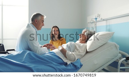 Professional friendly doctor meeting a senior patient on a hospital bed and her daughter, senior care concept Royalty-Free Stock Photo #1670749819