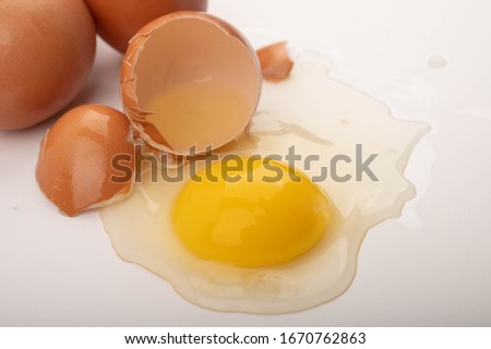 Broken chicken egg and eggs scattered on a white background. Close up.