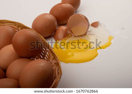 A broken chicken egg, eggs in a wicker basket, and eggs scattered on a white background. Close up.