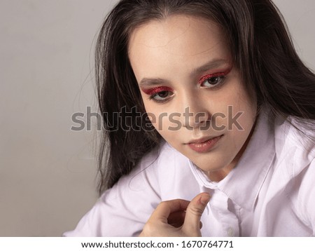 Portrait of a beautiful girl teenager. Conceptual makeup, red eyelashes and sequins. Healthy smooth skin.