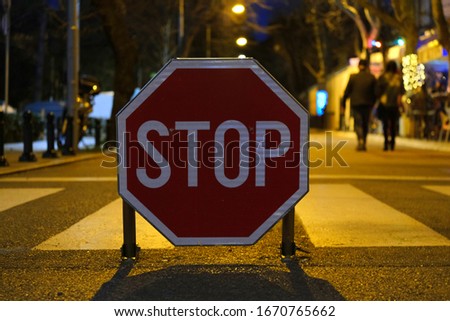Stop sign in the night in front of cross walk, blurry background