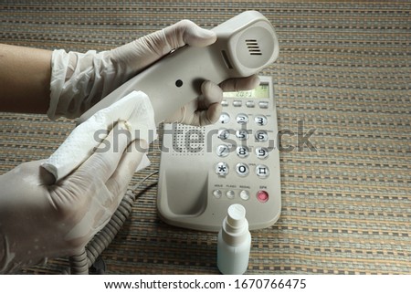 Cleaning staff cleaned public telephone with alcohol spray and wipe out with clean paper. Corona virus or bacteria infected protection from touching public object.  Royalty-Free Stock Photo #1670766475