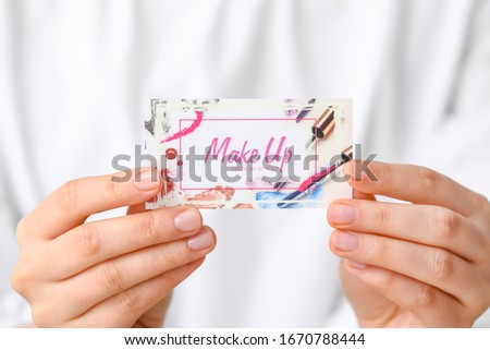 Woman with business card of makeup artist, closeup