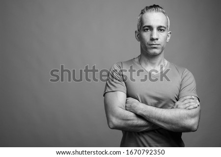 Handsome Persian man with gray hair against gray background