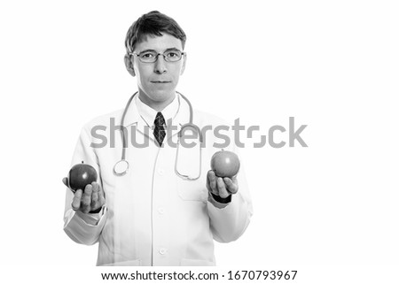 Studio shot of man doctor holding red apple and green apple