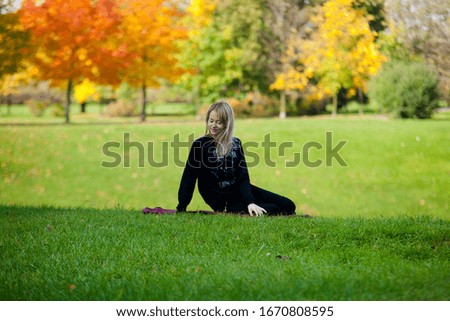 Young stylish blonde woman in black clothes with bordo scarf in city park