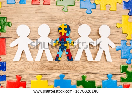 Top view of bright pieces of puzzle and special kid with autism among another on wooden background