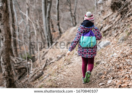 Children hiking in the mountains or woods on family trip. Active family, parents and children mountaineering in the nature. Kids are walking in woods trail road in cold winter time.