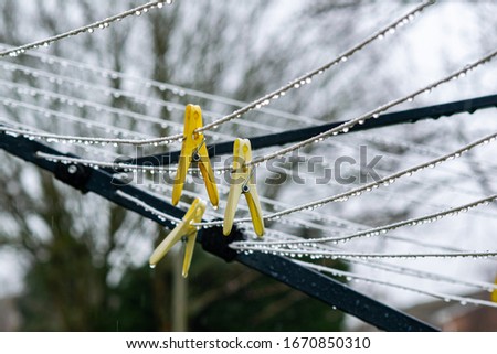 Yellow laundry clips in the rain, wet laundry drainer, bad time for drying clothes water drops on strings with clothes pins pegs