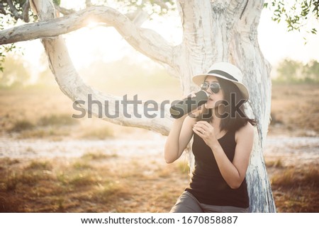 Happy traveller asian woman drinking water from the bottle in sunset time at forest,Lifestyle travel outdoor concept