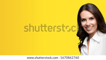 Happy smiling beautiful young confident businesswoman, with copy space area for some slogan or text. Success in business concept picture. Orange yellow color background.