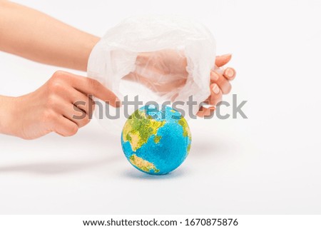 Partial view of woman holding plastic bag above globe on white, global warming concept