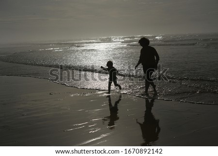 mother and child against the light playing on the beach