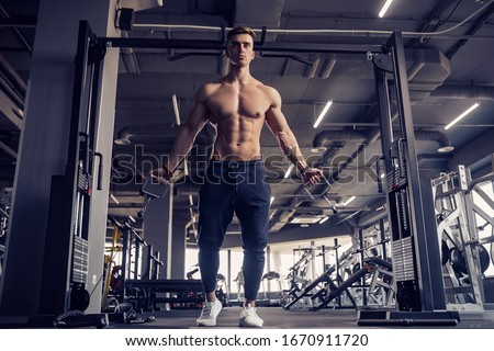 Muscular Fitness Bodybuilder Doing Heavy Weight Exercise For Pectoral Muscles On Machine With Cable In The Gym. Royalty-Free Stock Photo #1670911720