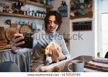 man cuddle with his dog in kitchen at home