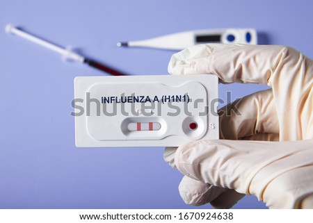 Doctor holding a test kit for viral diseases H1N1 flu and COVID-19 2019-nCoV. Lab card kit tested NEGATIVE for viral novel coronavirus sars-cov-2 virus and POSITIVE for H1N1 Royalty-Free Stock Photo #1670924638