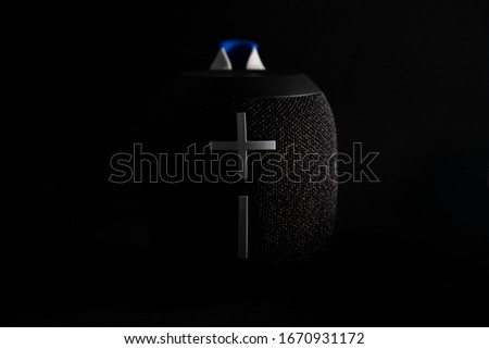 Minimalist black background close up of a wireless music speaker