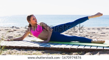Woman 28-35 years old is practicing yoga on the beach near sea. Royalty-Free Stock Photo #1670974876