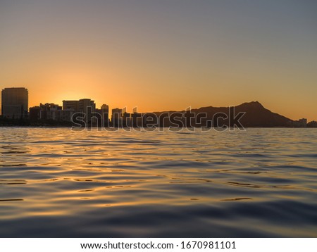 Ocean Scene of an Island Sunrise.  Boat view of the sun rising above land and illuminating the ocean.