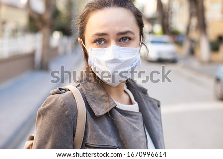 Young woman with face mask on the street. Novel Chinese Coronavirus self-protection concept Royalty-Free Stock Photo #1670996614