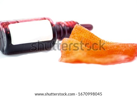 Studio macro of a pharmacy flask filled with a red liquid with a compress on a white background. Copy space.