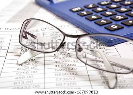 Glasses and calculator on paper table with finance report 