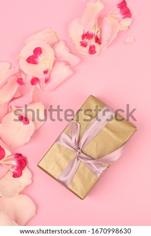 Floral frame with gold gift box on pink background. Greetings concept
