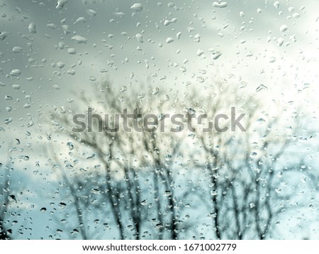 Wet window with rain drops and a cloudy sky outside background.