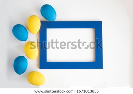 Easter card. Eggs painted in classic blue and pastel yellow colors on a white background. Blue frame for text. Minimalism. Copy space.