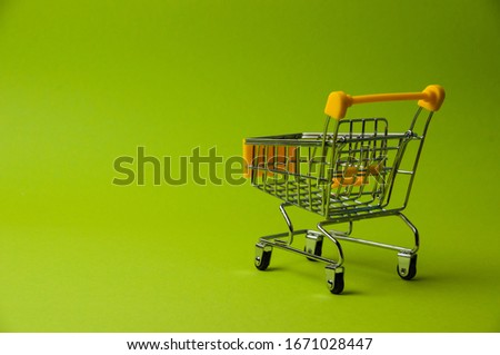 Trolley for shopping on a green background. Supermarket food price concept, holiday discounts