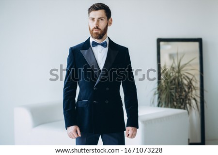 Successful Caucasian man in dark blue tuxedo and white shirt.