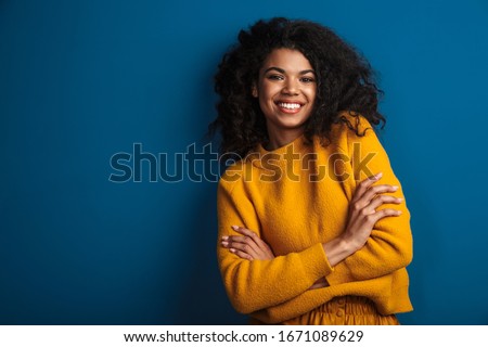 Image of a pretty cheerful optimistic young african woman posing isolated over blue wall background.