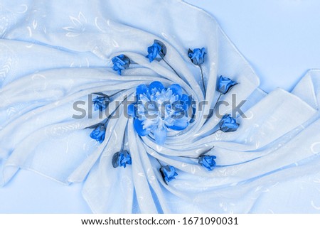 peony flower bud and artificial roses on blue fabric, top view flat lay tinting classic blue color