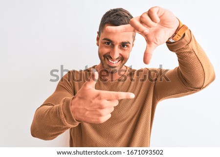 Young handsome elegant man wearing winter sweater over isolated background smiling making frame with hands and fingers with happy face. Creativity and photography concept.