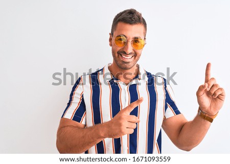 Young handsome man wearing summer sunglasses over isolated background smiling and looking at the camera pointing with two hands and fingers to the side.