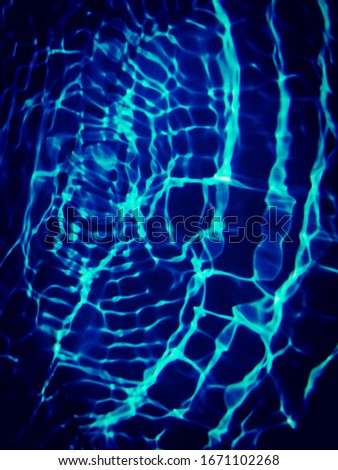 The​ pattern​ of​ surface​ blue​ water in​ the swimming​ pool reflected​ with​ sunlight​ for​ blue​ background. Abstract​ of​ surface​ blue​ water​ in​ the​ deep sea​ use​ for​ graphic​ design​
