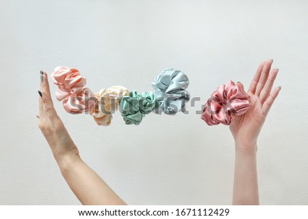 Lot of floating Colorful silk Scrunchies on womas hands isolated white. Hairdressing tools and accessories. Hair Scrunchies, Elastic HairBands, flying or falling Scrunchie Hairband for girl. copy Royalty-Free Stock Photo #1671112429