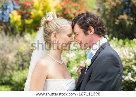 Pretty wife touching noses with new husband in the countryside